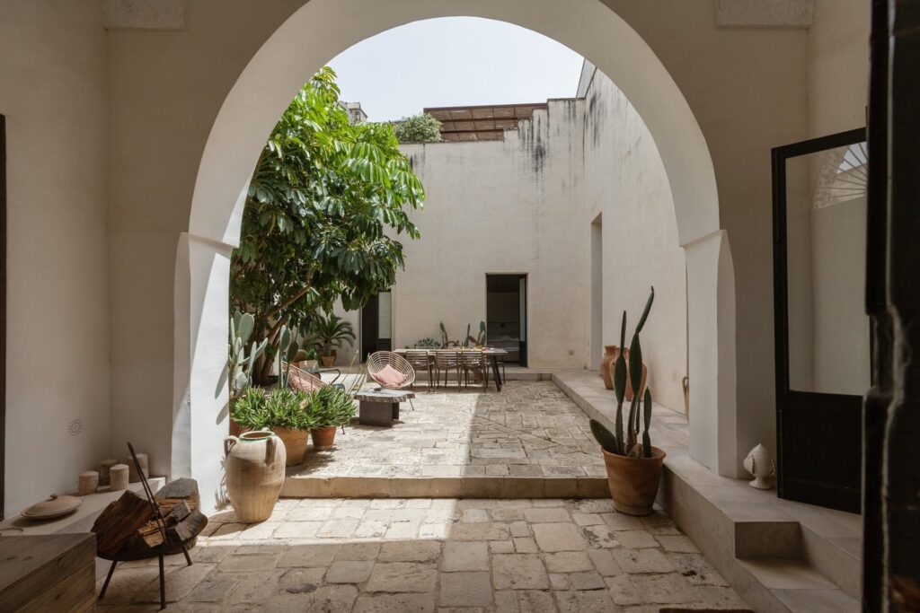 1. La_Corte_Nardòsalento_Credits40Mirrors_098_Courtyard entry view Arched entrance opening onto the stone courtyard, La Casa Grande, Nardò
