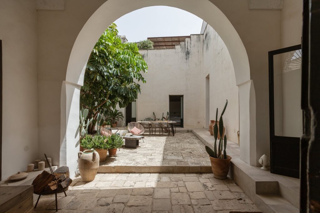 Arched entrance opening onto the stone courtyard at La Corte palazzo, Nardò