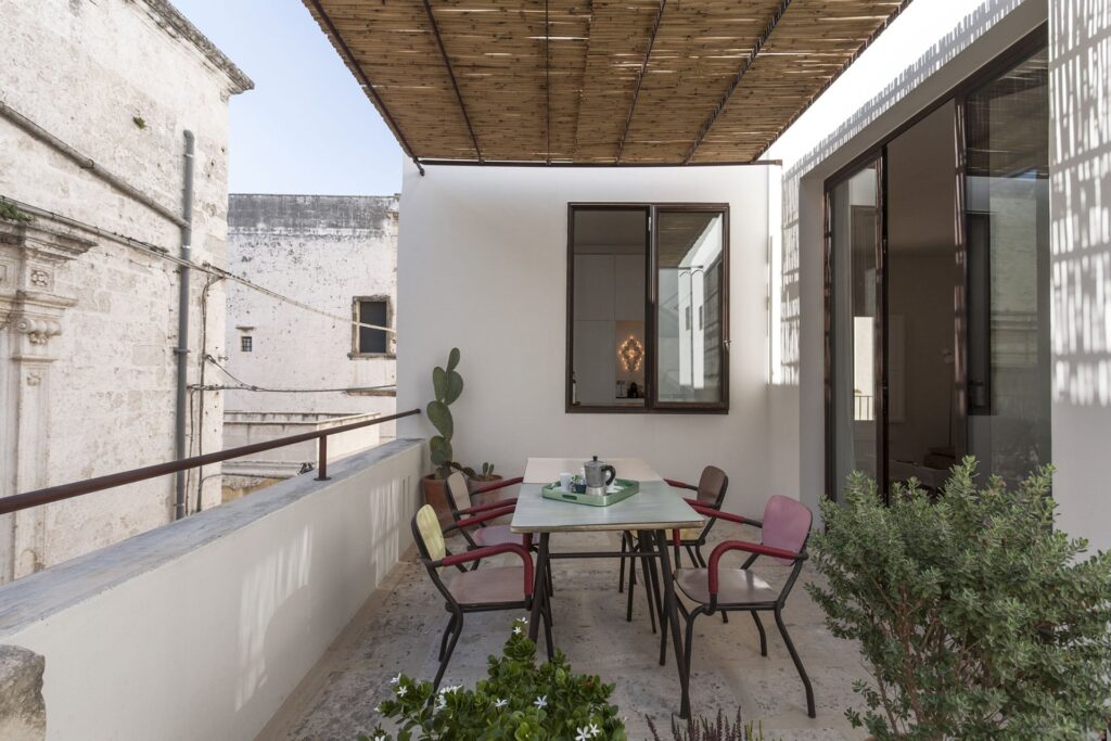 First-floor terrace with pergola shade and a mismatched dining set, Teatro house, Nardò