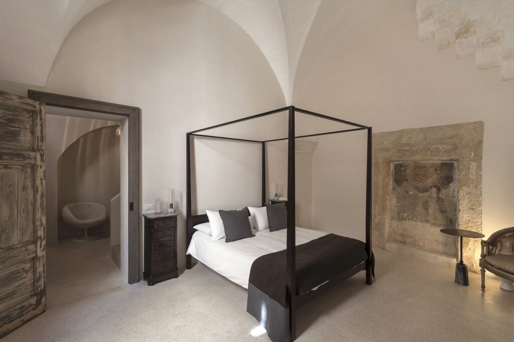 Master bedroom with canopy bed and an antique stone wall niche, Teatro house, Nardò