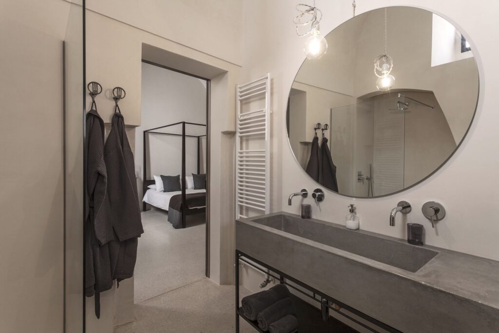 Ensuite bathroom with round mirror and concrete trough sink, Teatro house, Nardò