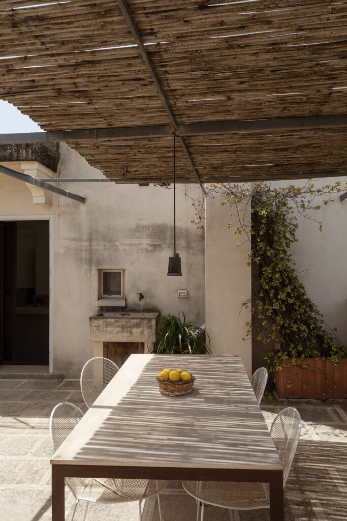 Covered terrace with reed pergola and a dining table set with lemons, Agrumeto house, Nardò