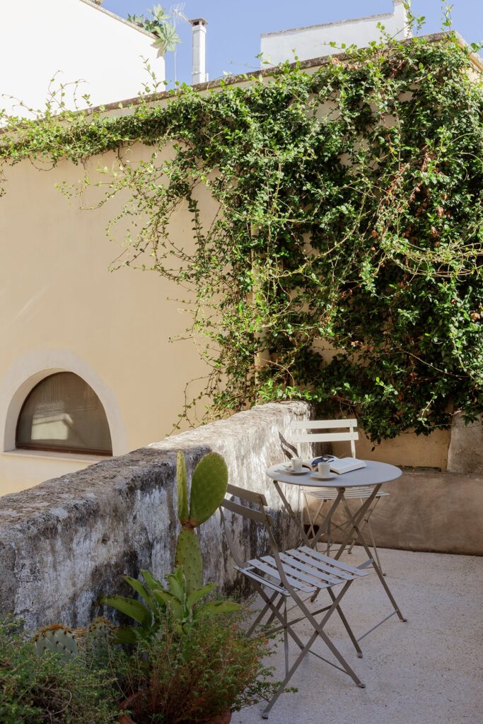 16. Angelo_Custode_Nardòsalento_Credits40Mirrors_51_First floor balcony First-floor balcony with a bistro table beneath cascading blooms, Angelo Custode, Nardò