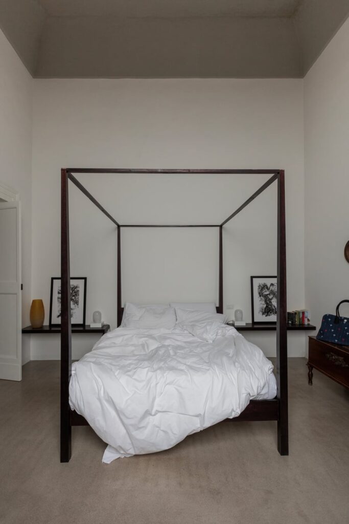 Bedroom with dark canopy bed frame and art prints, La Corte palazzo, Nardò