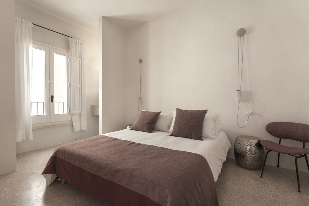 Second bedroom with burgundy linens and wall-mounted reading light, Teatro house, Nardò