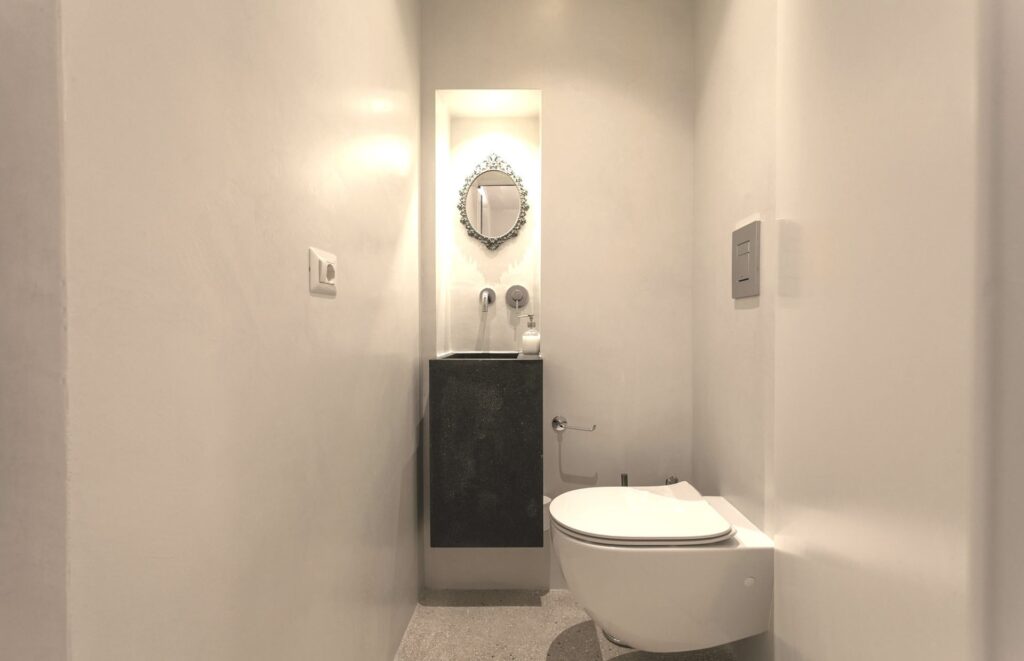 First-floor powder room with an antique mirror in a lit niche, Teatro house, Nardò