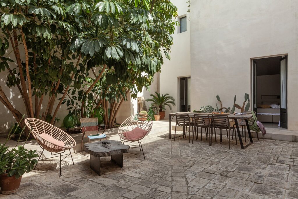 Courtyard dining table beneath a large tree at La Corte palazzo, Nardò