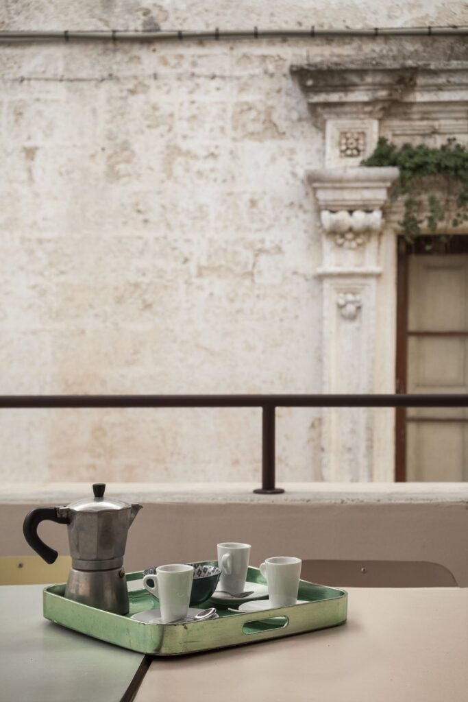 Moka pot and espresso cups on the terrace overlooking a stone facade, Teatro house, Nardò
