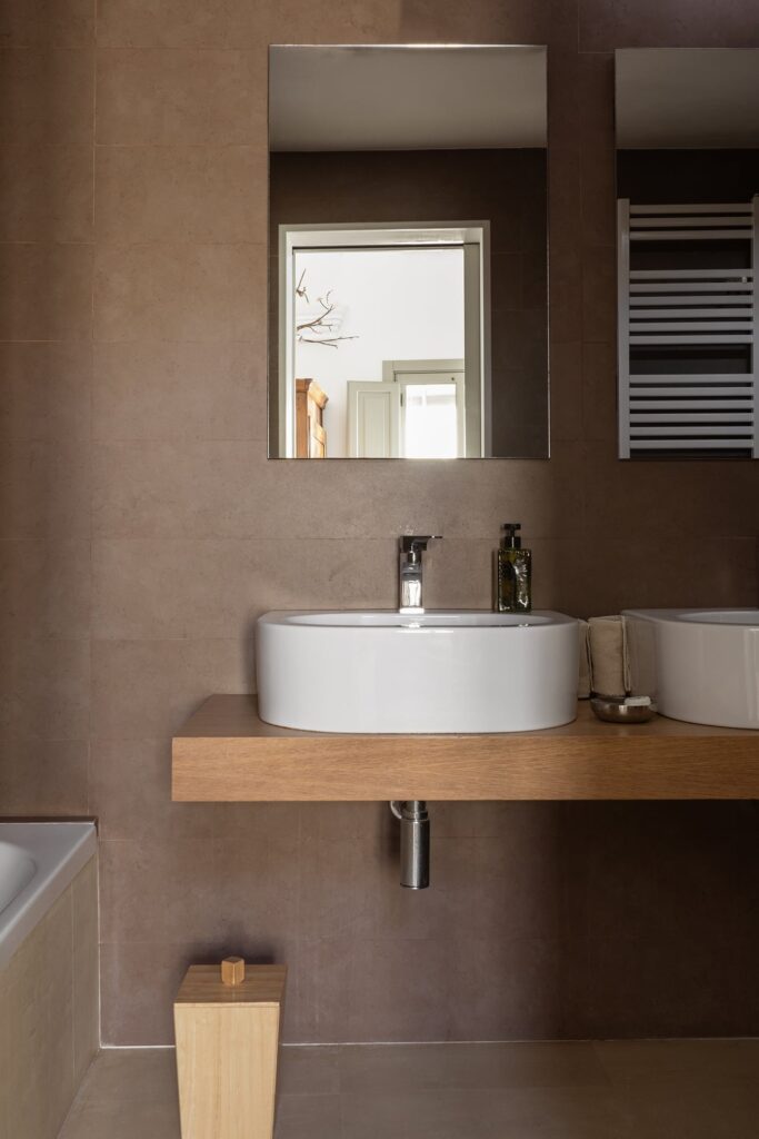 23. Angelo_Custode_Nardòsalento_Credits40Mirrors_15_Master bedroom_ensuite bathroom Master ensuite bathroom with double vanity in dark tile, Angelo Custode, Nardò