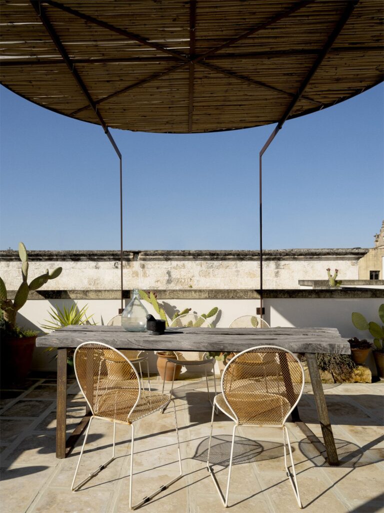 Rooftop terrace dining table beneath a reed pergola, Teatro house, Nardò
