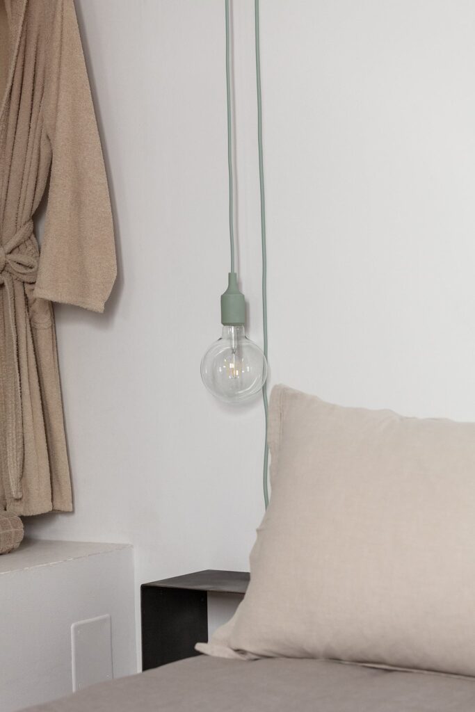 25. Angelo_Custode_Nardòsalento_Credits40Mirrors_24_Bedroom 2 detail Bedroom wardrobe detail with a robe and hanging bulb light, Angelo Custode, Nardò