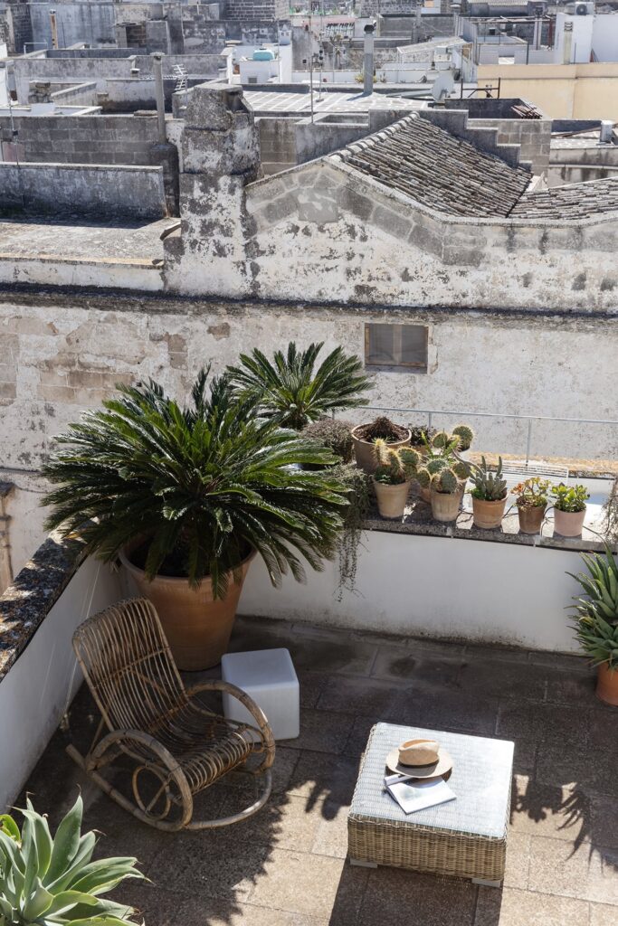 30. Angelo_Custode_Nardòsalento_Credits40Mirrors_84_Highest terrace views Highest terrace lounge corner with rocking chair and potted palms, Angelo Custode, Nardò