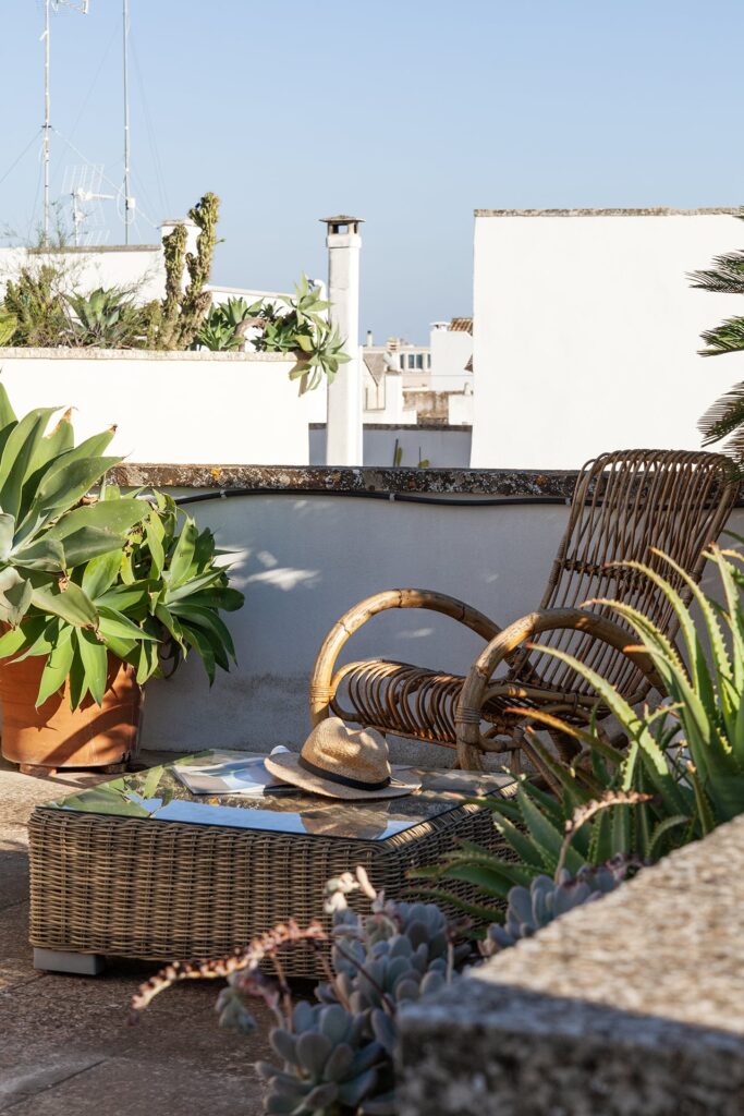 31. Angelo_Custode_Nardòsalento_Credits40Mirrors_96_Rooftop terrace detail Rooftop terrace seating with a straw hat on the side table, Angelo Custode, Nardò
