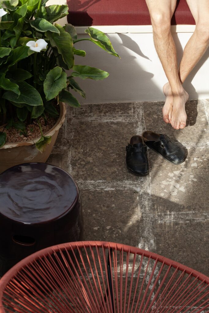 Bare feet and slippers on the rooftop lounge floor, La Corte palazzo, Nardò
