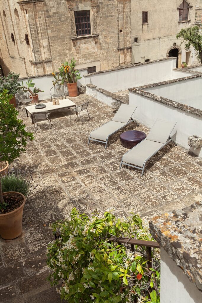 Rooftop terraces seen from the upper level, with lounge chairs and cacti, La Corte, Nardò