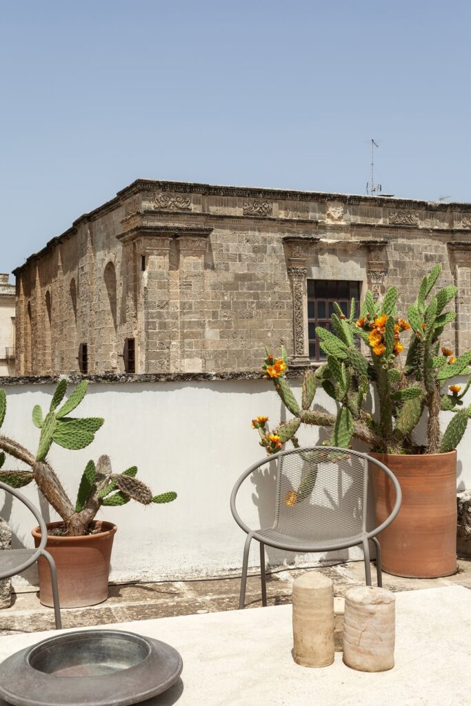 Rooftop terrace with flowering cacti and a view of the stone palazzo facade, La Corte, Nardò