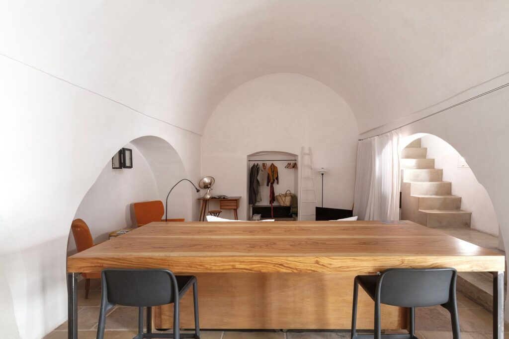 Barrel-vaulted living space with wooden dining table at La Botte loft, Nardò