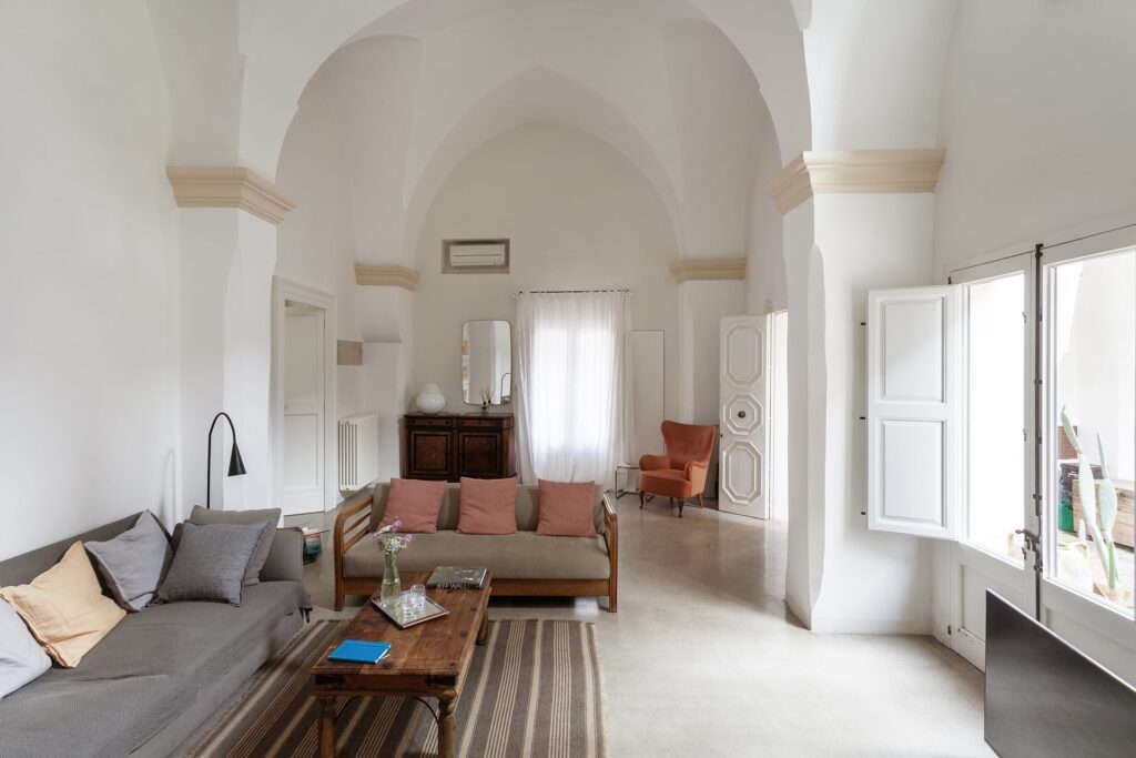 Living room with double groin-vaulted ceiling and grey sofas, La Corte, Nardò