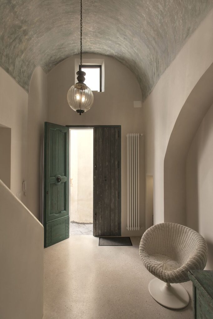 Vaulted entry hall with glass pendant light and green door, Teatro house, Nardò