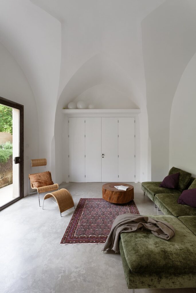 Living room with vaulted ceiling and olive green velvet sofa, Agrumeto house, Nardò