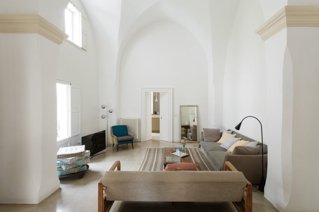 Living room with vaulted ceiling and a blue accent chair, La Corte, Nardò