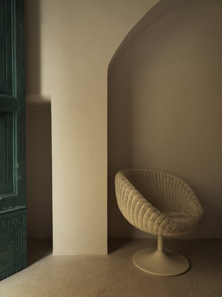 Woven rattan chair in an arched alcove, Teatro house entry, Nardò