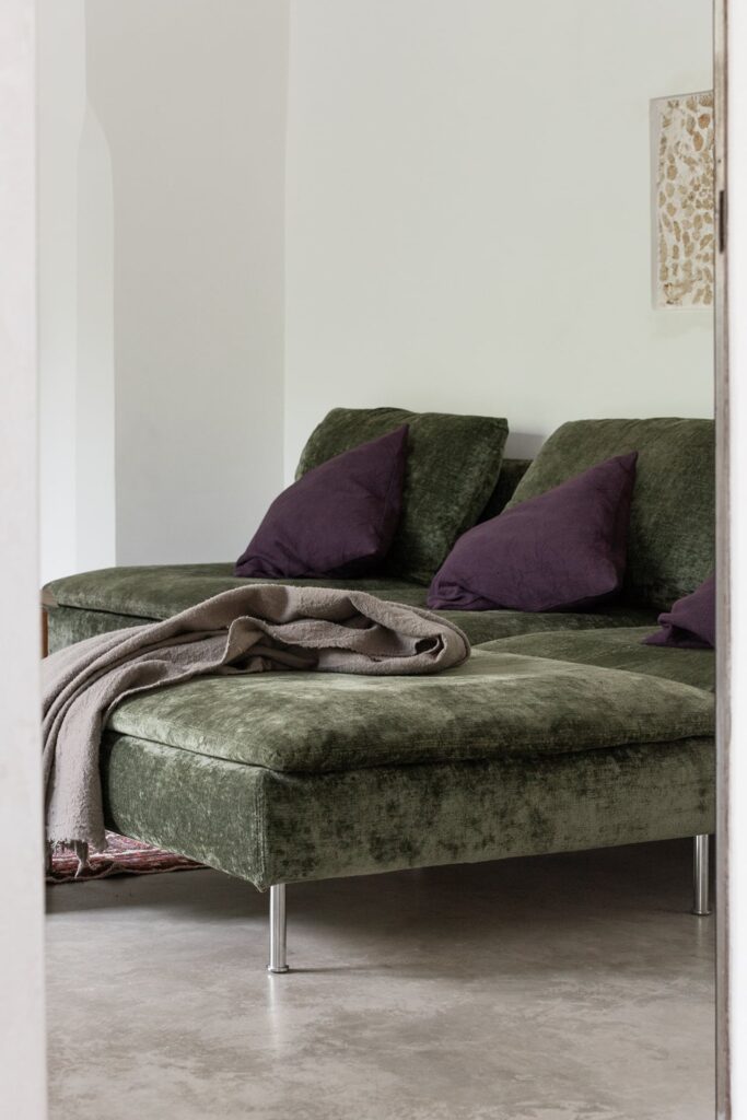 Living room daybed detail with plum cushions and a linen throw, Agrumeto house, Nardò