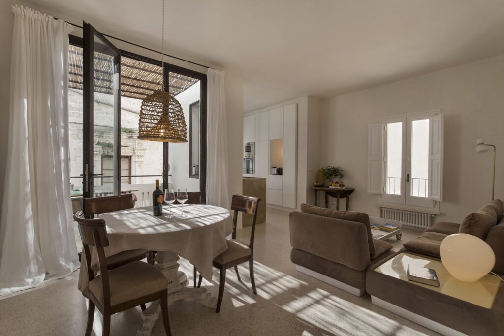 Living space with round dining table and terrace doors open, Teatro house, Nardò