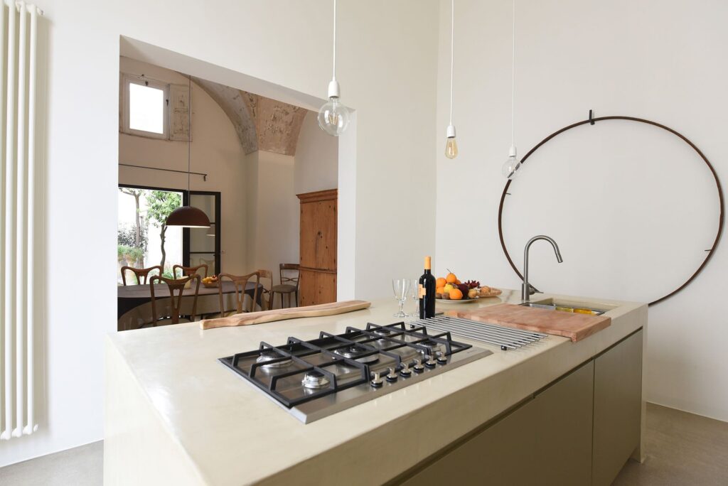 Kitchen island detail with gas hob and view to the dining room, La Corte, Nardò