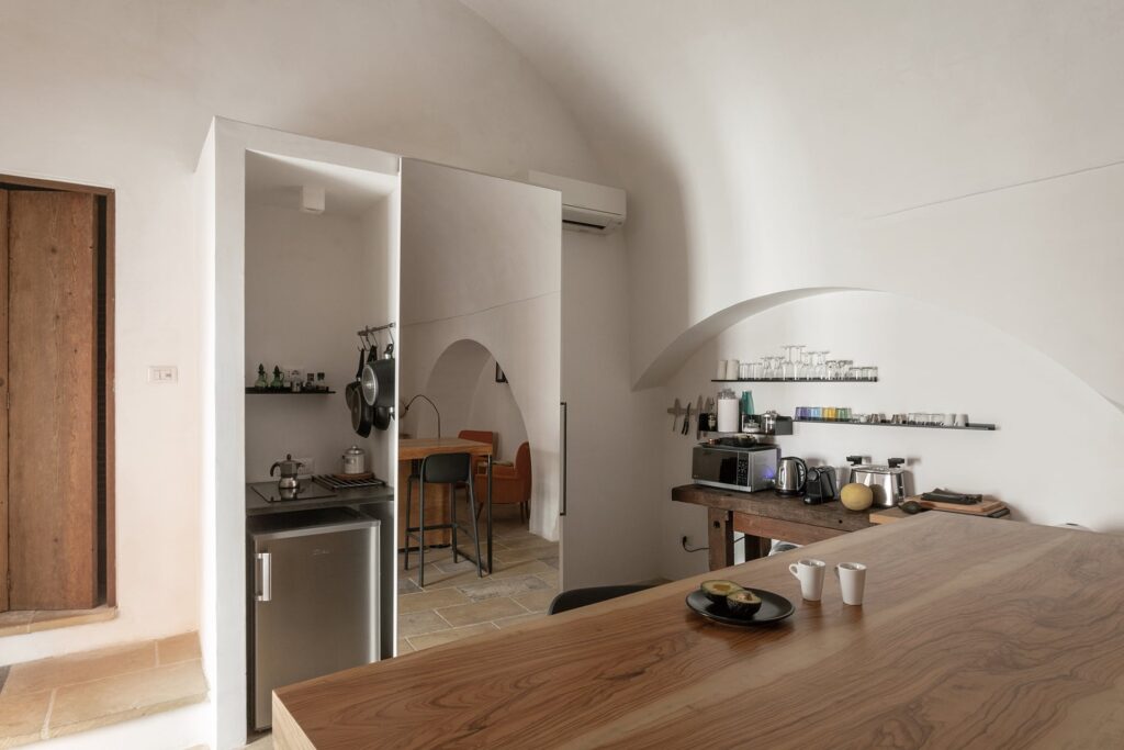 Compact kitchenette with open shelving and vaulted ceiling at La Botte, Nardò